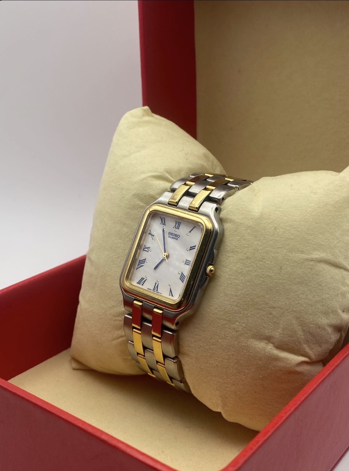A two-tone Seiko presented on a cream cushion inside its red presentation box